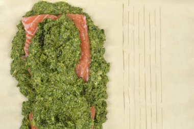 Cömert bir ıspanak karışımı katılmış somon filetosu, fırınlanmaya hazır bir puf böreğinin üzerine yerleştirilmiş.