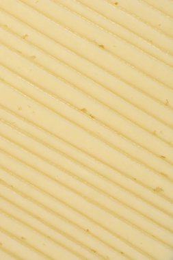 Yakın çekim, istiflenmiş peynir dilimlerinin dokusunu, çapraz çizgiler oluşturarak gösterir.