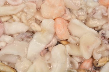 Donmuş deniz ürünleri, mürekkep balığı, midye ve karides parçalarıyla yakın çekim görüntüsü.