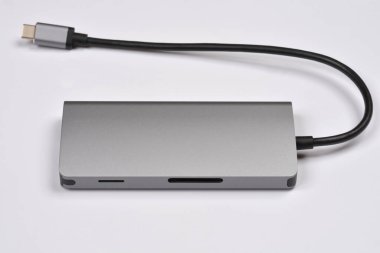 Açık gri arkaplanda birden fazla porta ve siyah kabloya sahip metalik gri bir USB-C merkezi gösterilir