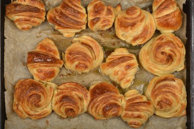 A delicious top-down view of freshly baked, golden croissants and pastries on a baking sheet