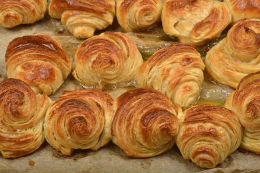 A  close-up of a baking sheet filled with freshly baked, golden-brown croissants and pastries