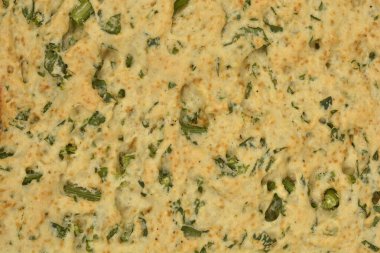 Pişmiş ev yapımı kraker yüzeyinin yakın plan bir görüntüsü. Kaba, açık kahverengi bir doku ve doğranmış yeşil maydanozu gösteriyor.