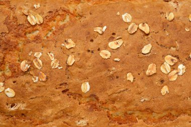 Kırsal, tam tahıllı bir ekmeğin kabuğunun yakın çekimi, dağınık yulaf ezmesi içeriyor.