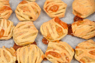 Taze pişmiş poğaçanın yakın plan görüntüsü, kafes deseninde eti dolduran, eritilmiş dolgu malzemesiyle çarşafın üzerine sergilenen.