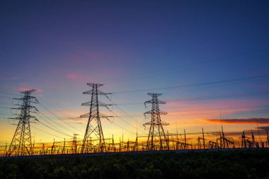 Elektrik iletim pilonu alacakaranlıkta mavi gökyüzüne karşı siluetlendi