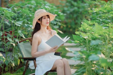 Kız bahçede kitap okuyor.