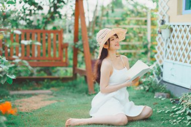 Kız bahçede kitap okuyor.