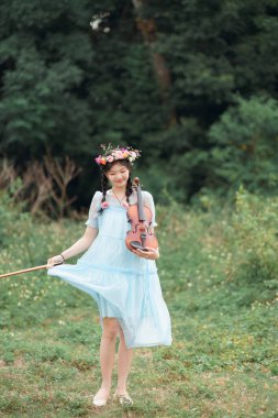 Kız büyük ağacın altında keman çalıyor.