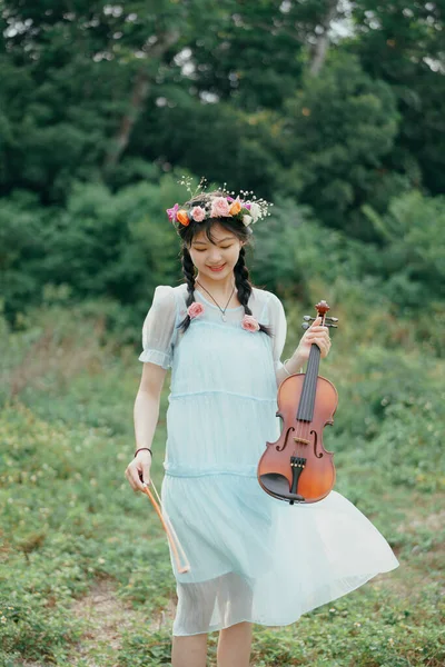 stock image The girl is playing the violin under the big tree