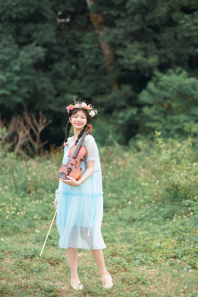 stock image The girl is playing the violin under the big tree