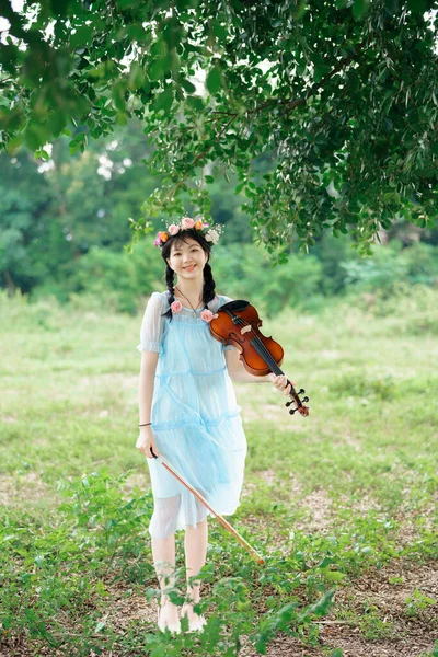 stock image The girl is playing the violin under the big tree