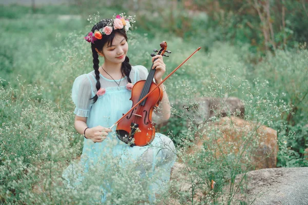 女の子は大きな木の下でバイオリンを弾いている — ストック写真