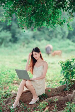 Kız ormanda dizüstü bilgisayar kullanıyor.