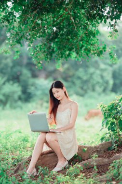 Kız ormanda dizüstü bilgisayar kullanıyor.