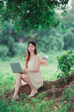 Kız ormanda dizüstü bilgisayar kullanıyor.