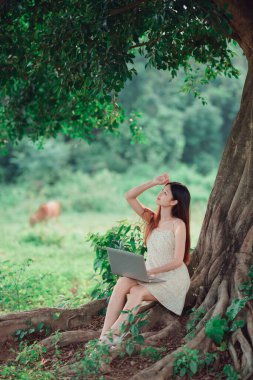 Kız ormanda dizüstü bilgisayar kullanıyor.