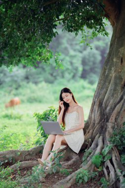 Kız ormanda dizüstü bilgisayar kullanıyor.