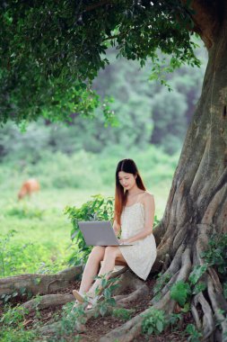 Kız ormanda dizüstü bilgisayar kullanıyor.