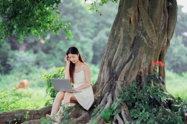 Kız ormanda dizüstü bilgisayar kullanıyor.