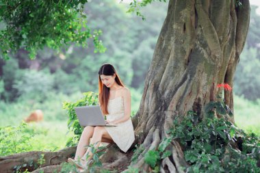 Kız ormanda dizüstü bilgisayar kullanıyor.