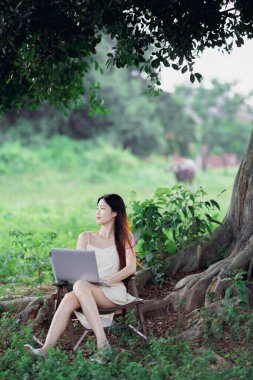 Kız ormanda dizüstü bilgisayar kullanıyor.