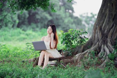 Kız ormanda dizüstü bilgisayar kullanıyor.