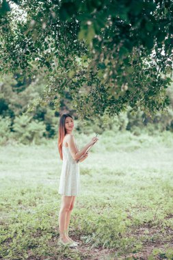 Kız büyük ağacın altında çizim yapıyor.