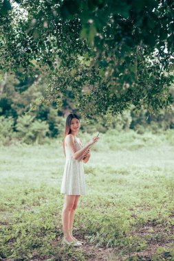 Kız büyük ağacın altında çizim yapıyor.