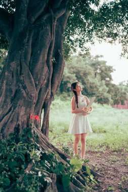 Kız büyük ağacın altında çizim yapıyor.