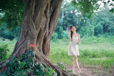 Kız büyük ağacın altında çizim yapıyor.