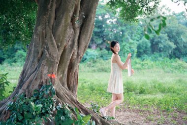 Kız büyük ağacın altında çizim yapıyor.