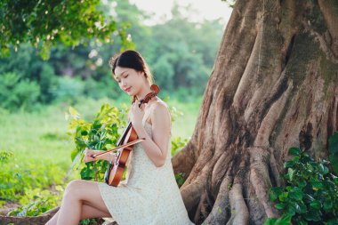 Genç kız ormanda keman çaldı.