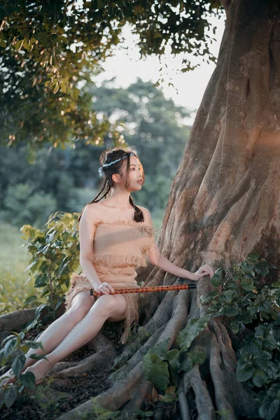 stock image nostalgic theme, girl playing flute under tree