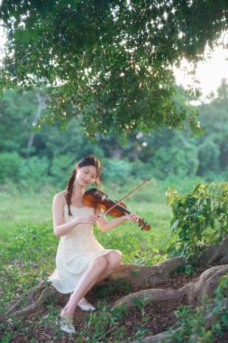 Genç kız ormanda keman çaldı.