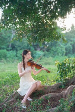 Genç kız ormanda keman çaldı.