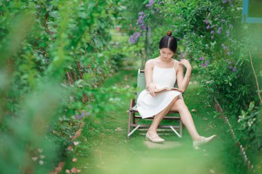 Kız bahçede kitap okuyor.