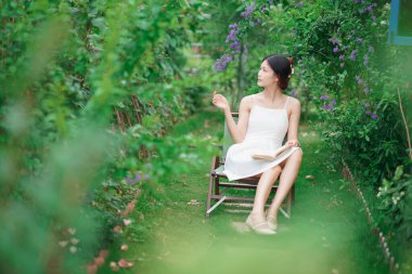 Kız bahçede kitap okuyor.