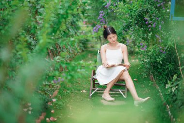 Kız bahçede kitap okuyor.