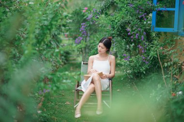 Kız bahçede kitap okuyor.