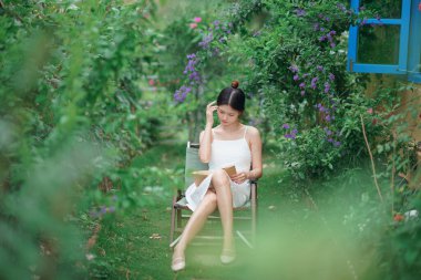 Kız bahçede kitap okuyor.