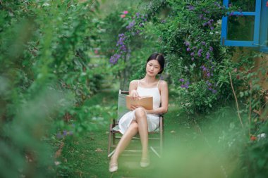 Kız bahçede kitap okuyor.