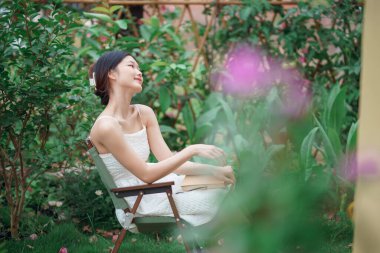 Kız bahçede kitap okuyor.