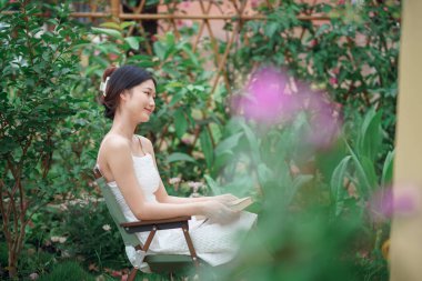 Kız bahçede kitap okuyor.