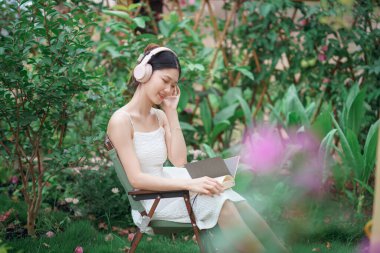 Kız bahçede kitap okuyor.