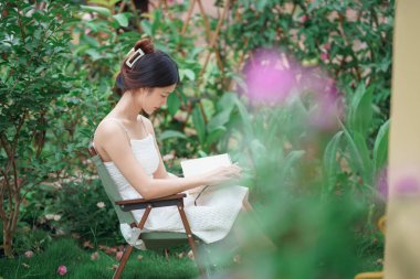 Kız bahçede kitap okuyor.