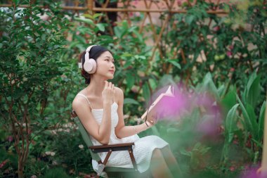 Kız bahçede kitap okuyor.