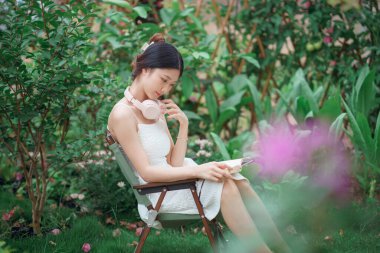 Kız bahçede kitap okuyor.