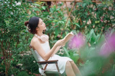 Kız bahçede kitap okuyor.