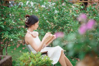 Kız bahçede kitap okuyor.